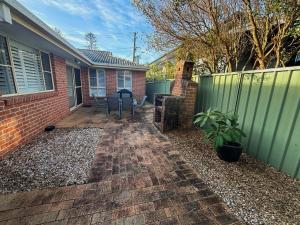 a backyard with a fence and a table and a grill at Baybreeze - Bring your own linen in South West Rocks