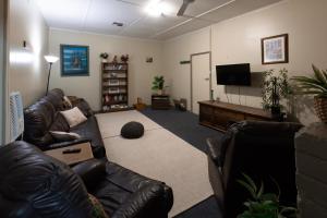 a living room with a leather couch and a flat screen tv at Broken Hill Tourist Lodge in Broken Hill