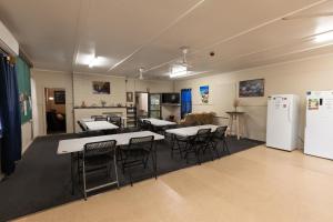 a room with tables and chairs and a kitchen at Broken Hill Tourist Lodge in Broken Hill
