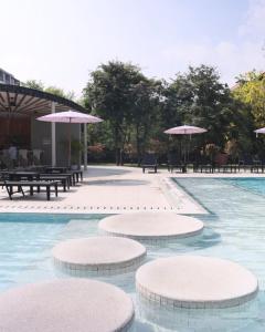 a swimming pool with tables and chairs and umbrellas at Pinnacle Grand Jomtien Resort and Beach Club in Na Jomtien