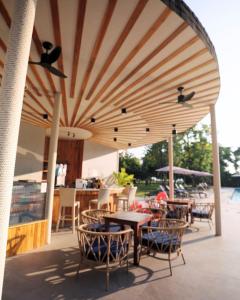 a patio with tables and chairs under a large umbrella at Pinnacle Grand Jomtien Resort and Beach Club in Na Jomtien