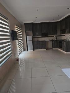 a kitchen with wooden cabinets and a white tile floor at Mafjoint5 in eMalahleni