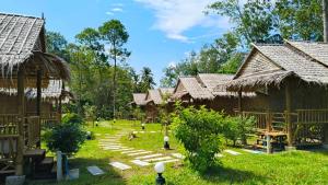 a group of huts in a village with grass at Mook Mellow Hill Bungalows in Ko Mook