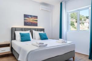 a bedroom with a bed with blue pillows and a window at Villa Virginia in Sarandë