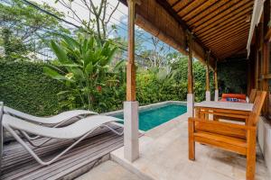 a patio with chairs and a table and a swimming pool at Alam Bidadari Seminyak in Seminyak