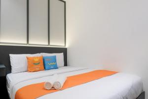a bedroom with a bed with orange and blue pillows at SANS Vibes Surya in Stasiun Tawang
