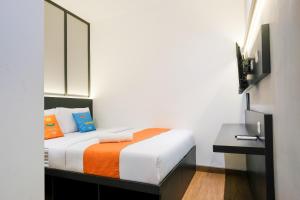 a bedroom with a bed with an orange and white blanket at SANS Vibes Surya in Stasiun Tawang