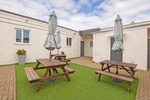 two picnic tables with umbrellas on the grass at Citi Hotel London Heathrow in Hillingdon