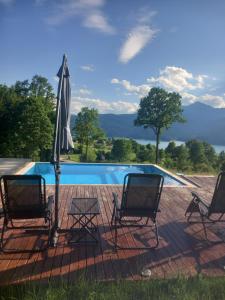three chairs and an umbrella next to a swimming pool at Perfect view cottage with pool in Buhalniţa