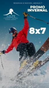 a man on skis in the snow with his arm in the air at Cabañas Sublime Bolson in El Bolsón