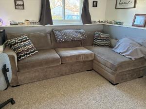 a brown couch in a living room with pillows on it at Ocean Town Homestay in Westerly