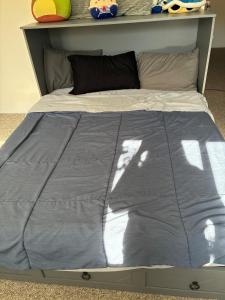 a bed with a blue comforter on top of it at Ocean Town Homestay in Westerly