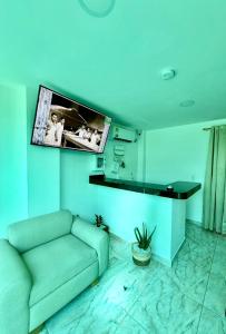 a living room with a couch and a tv on the wall at Hostal La Marina in Santa Marta