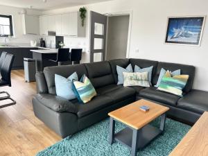 a black leather couch in a living room with a table at Caledonia Place in Aviemore