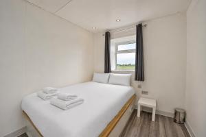 a white bed in a room with a window at Citi Hotel London Heathrow in Hillingdon