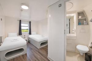 a white room with two beds and a mirror at Citi Hotel London Heathrow in Hillingdon