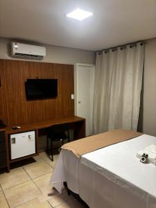 a bedroom with a bed and a desk with a television at Blume Suítes Premium Orla in Petrolina