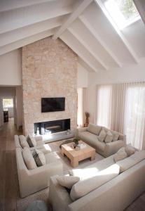 a living room with white furniture and a stone fireplace at Moso House Pearl Beach in Pearl Beach +50 photos