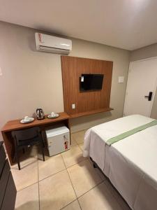 a bedroom with a bed and a desk and a television at Blume Suítes Premium Orla in Petrolina