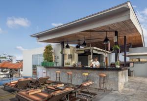 an outdoor bar with chairs and a man in a kitchen at Sevn Legian in Legian