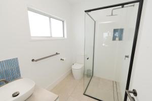 a bathroom with a glass shower stall and a toilet at Quampi House with Best Ocean View in Point Lookout