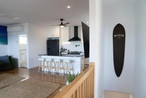 a kitchen and living room with a counter and stools at Quampi House with Best Ocean View in Point Lookout +16 photos