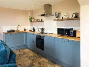 a kitchen with blue cabinets and a counter top at The Old Stable At Henley View in Draycott