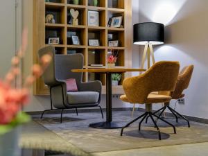 a table with chairs and a lamp in a room at Mercure Hotel Stuttgart Airport Messe in Stuttgart +163 photos