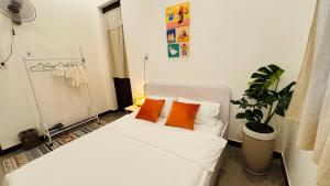 a bedroom with a white bed with two orange pillows at Ni Nớ Home in Hue