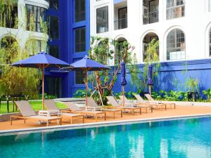 a group of chairs and umbrellas next to a pool at Above Element Bangtao Phuket by Arthouse Collection in Laguna Phuket