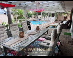 a patio table with chairs and an umbrella and a pool at Edgewater Whole Holiday Resort in Perth