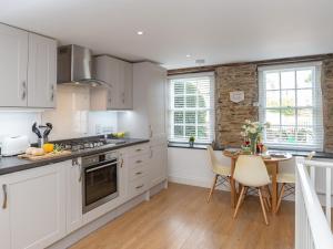 a kitchen with white cabinets and a table and chairs at Dayan Cottage in Fowey