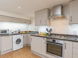 a kitchen with white cabinets and a washer and dryer at Dayan Cottage in Fowey +15 photos