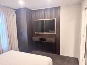 a room with a bed and a tv on a wall at Manukau Hotel & Conference Centre in Auckland