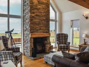 a living room with a stone fireplace and chairs at Ryka Lodge in Back