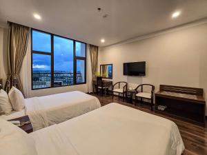 a hotel room with two beds and a flat screen tv at Indochine Hotel in Kon Tum (2)
