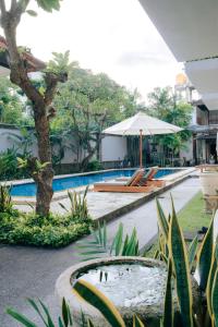 a pool with chairs and an umbrella next to a resort at New Puri Asih Hotel in Kuta