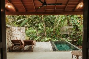 a patio with a pool and two chairs and a table at DreamTime in Hikkaduwa
