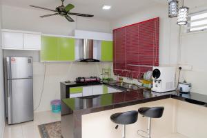 a kitchen with green and white cabinets and a refrigerator at Deeja Homestay Kuantan in Kuantan