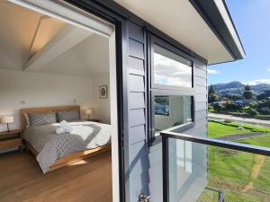 a bedroom with a bed and a large window at Serenity Sands Beach House in Hahei +40 photos