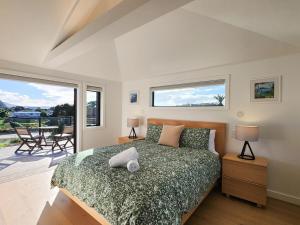 a bedroom with a bed and a large window at Serenity Sands Beach House in Hahei
