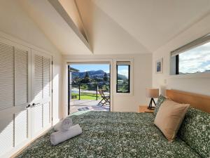 a bedroom with a bed and a large window at Serenity Sands Beach House in Hahei