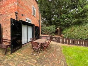 a wooden table and chairs next to a brick building at Saddle Room - Uk51017 in Louth