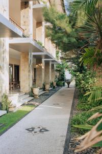 a walkway in front of a building with palm trees at New Puri Asih Hotel in Kuta