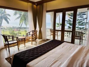 a bedroom with a bed and a view of the ocean at Maadathil Cottages & Beach Resort in Varkala