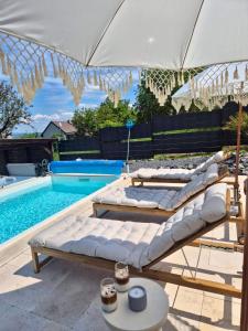 three lounge chairs and an umbrella next to a pool at Gyémánt Vendégház in Doba
