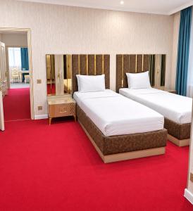 two beds in a hotel room with red carpet at Central City Department Hotel in Baku