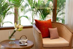 ein Korbsessel mit einer Blumenvase und einem Tisch in der Unterkunft FCC Angkor by Avani in Siem Reap