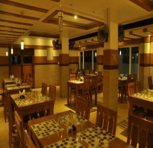 a restaurant with tables and chairs in a room at Hotel PAMS in Mayiladuthurai