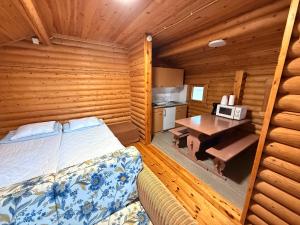 a bedroom with a bed and a desk in a cabin at Kolmiloukon leirintämökit in Taivalkoski